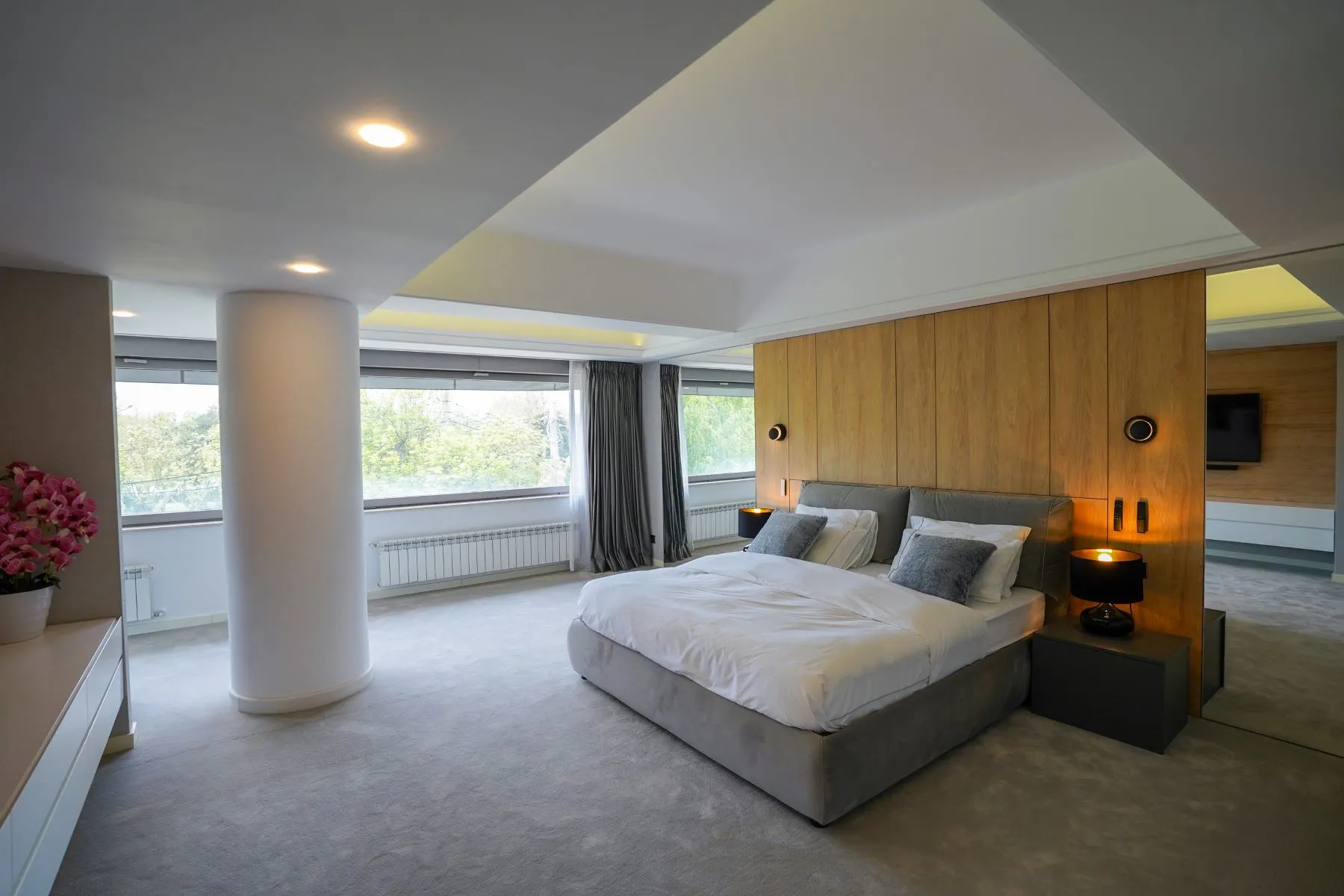 Exceptional principal suite with grey bed, lounge seating and wraparound windows