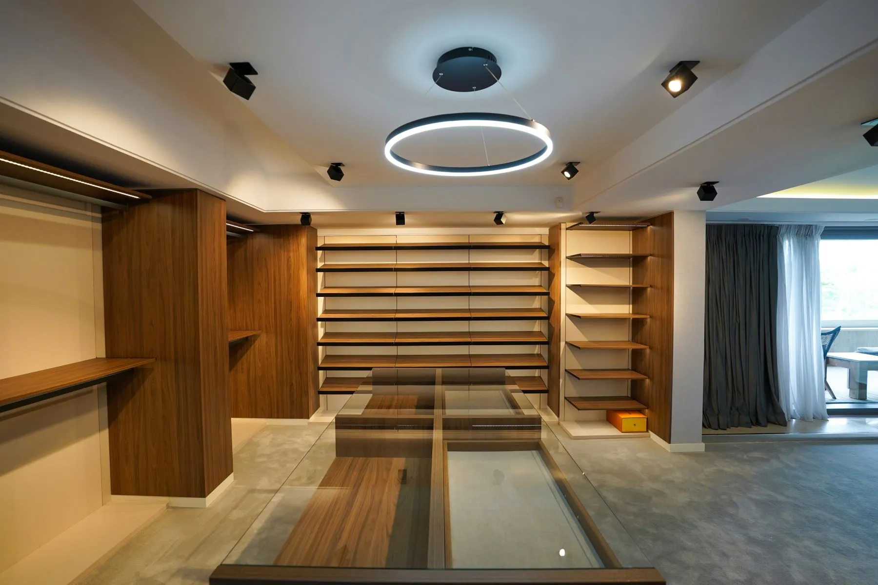 Walk-in wardrobe with extensive timber shelving and central glass-topped island