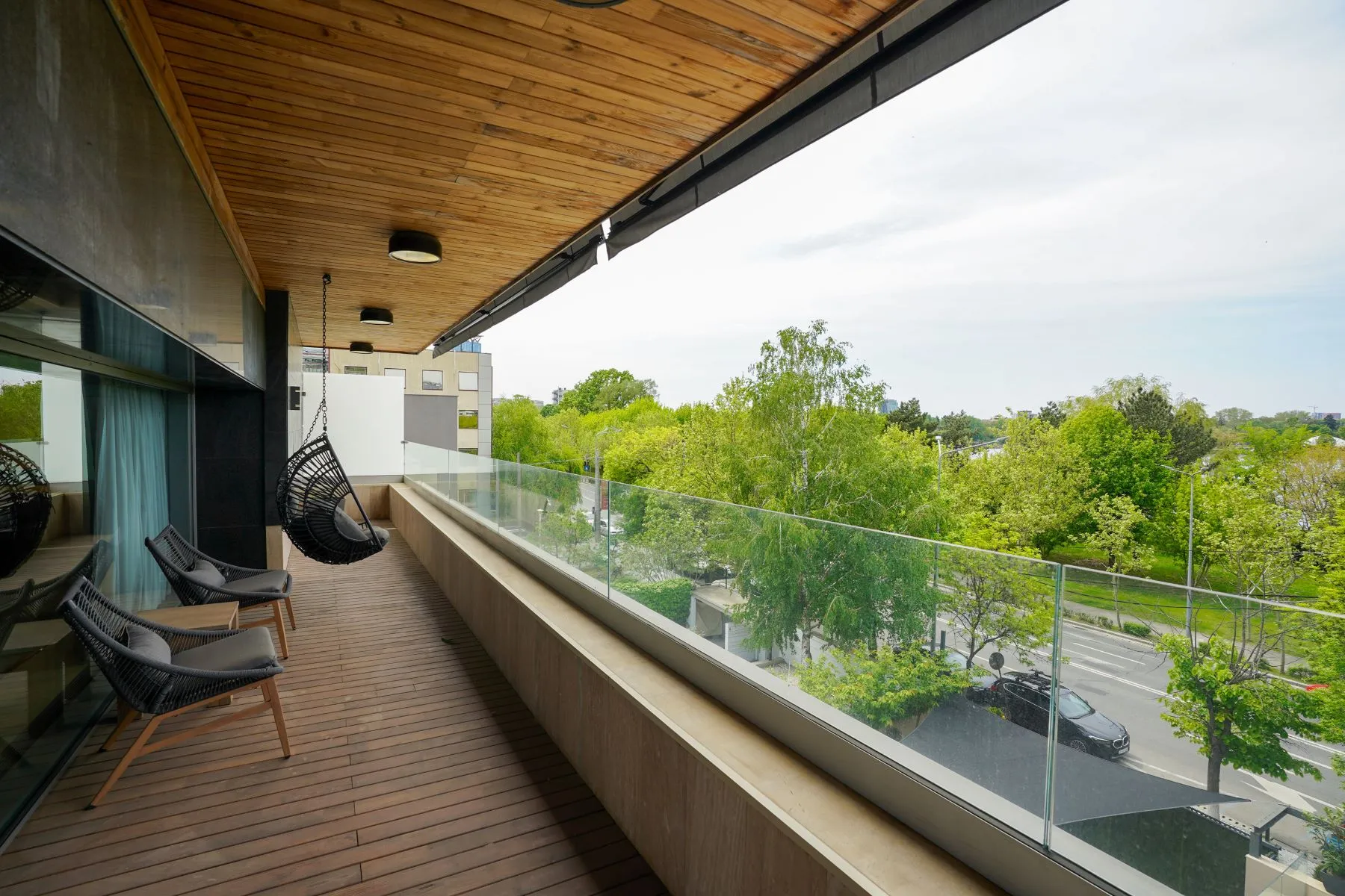 Long private upper-floor balcony with glass balustrade and treetop outlook