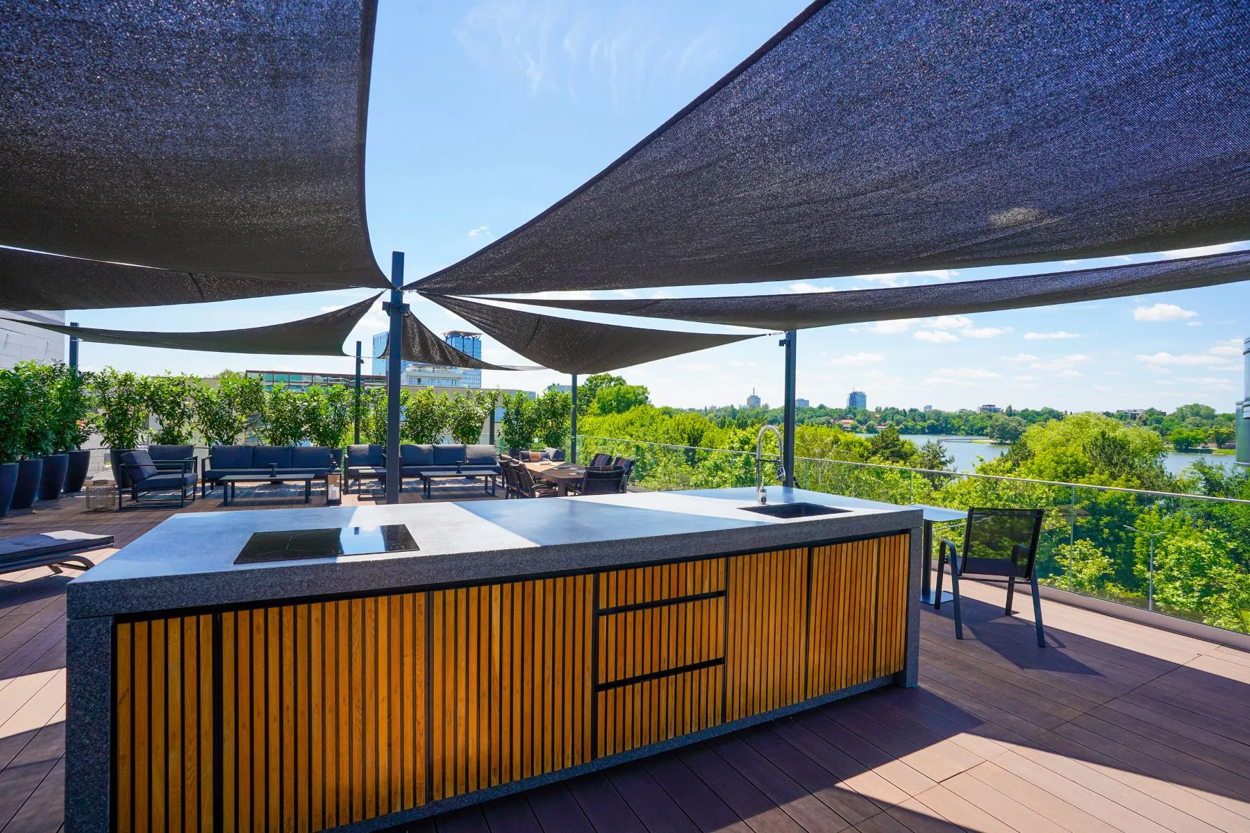 Rooftop bar beneath architectural shade sails with panoramic lake views