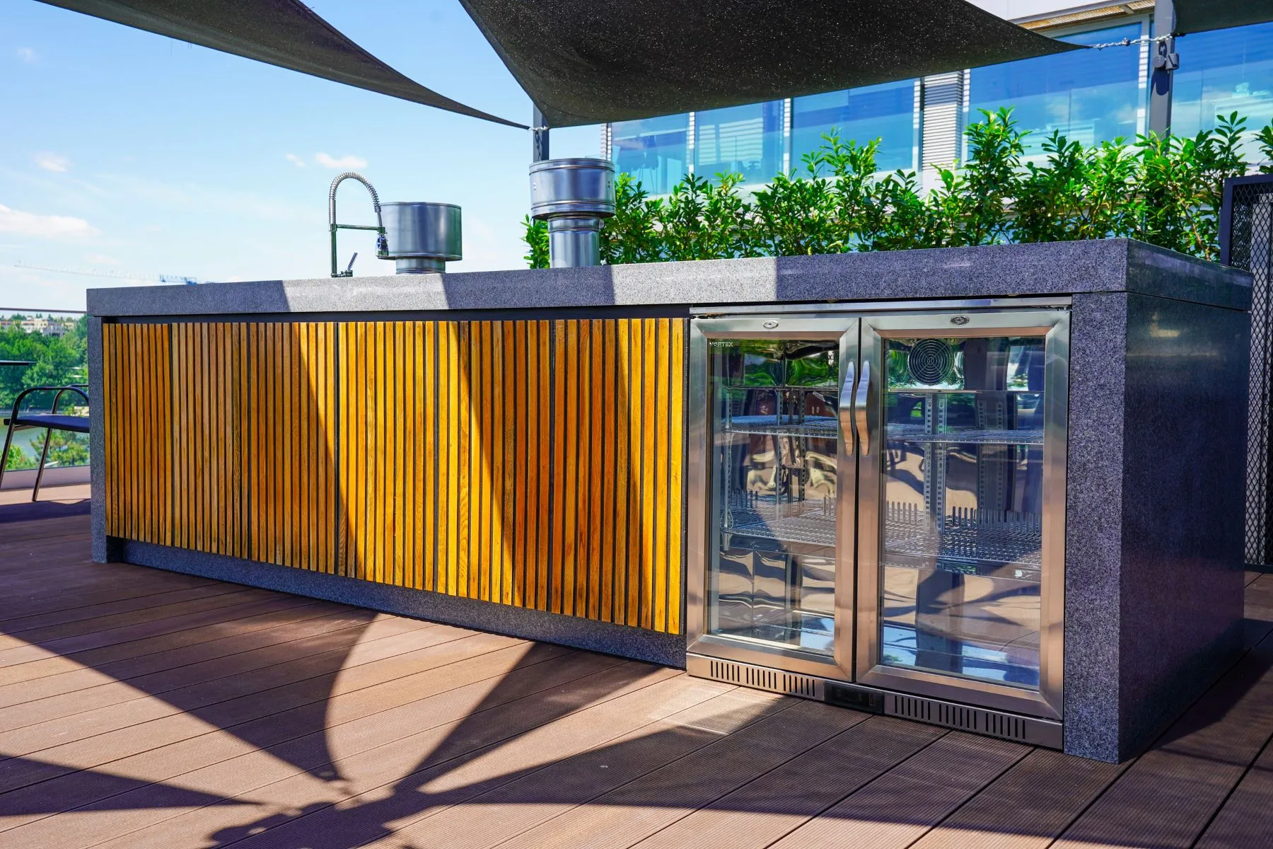Fully equipped rooftop bar with glass-fronted refrigerator and timber cladding