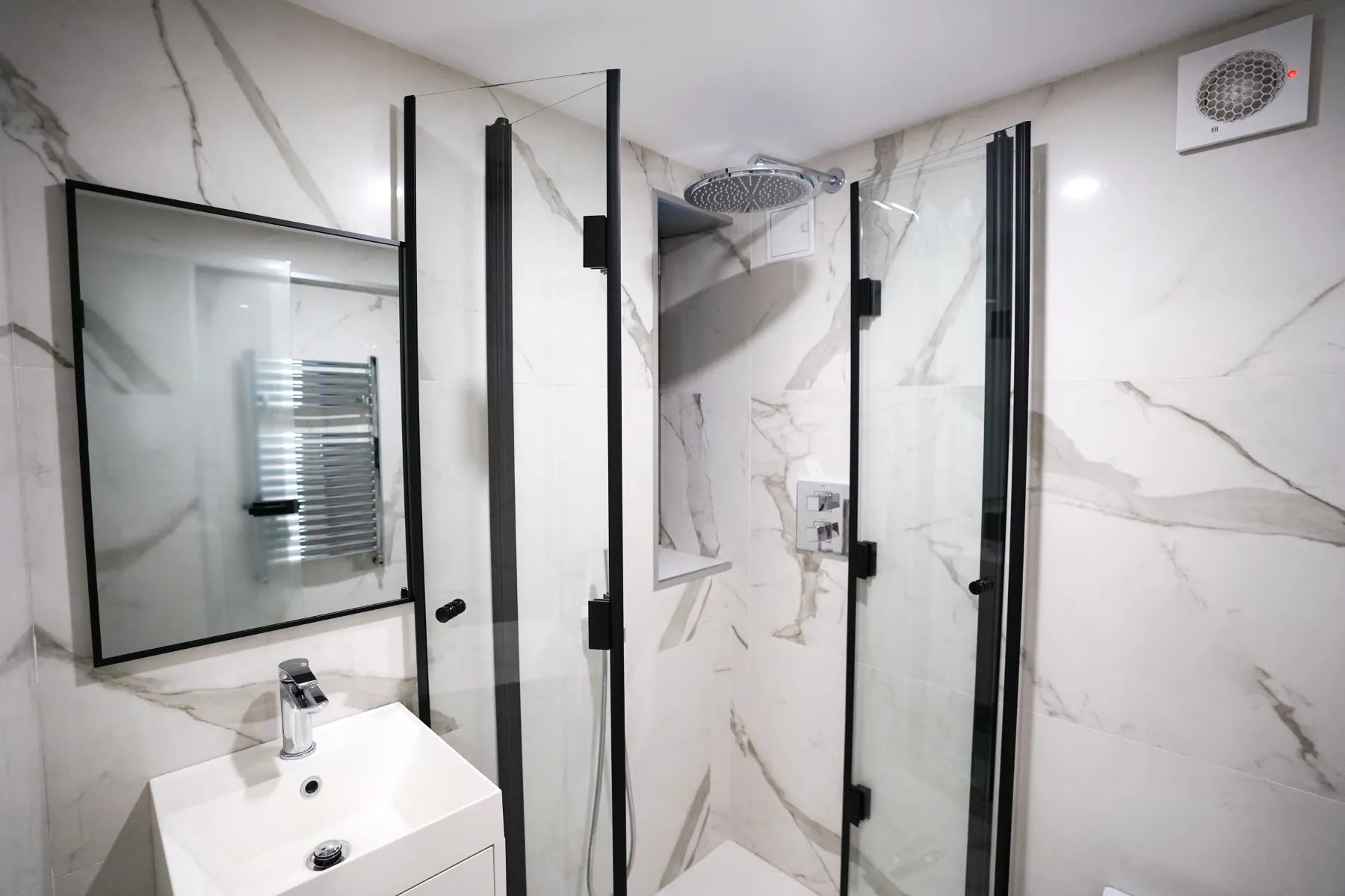 Compact marble shower room with glass enclosure and wall-mounted basin