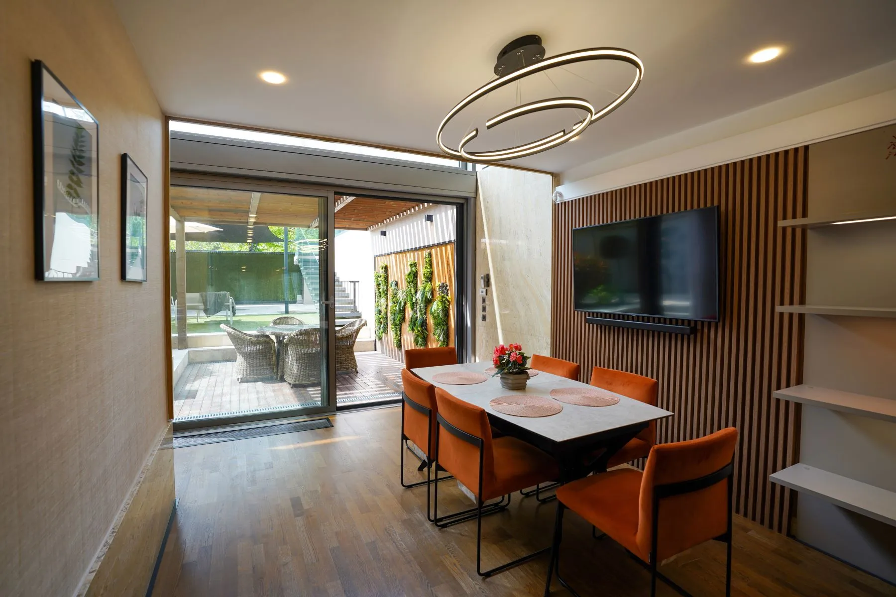 Contemporary dining room with orange chairs and doors to the garden terrace
