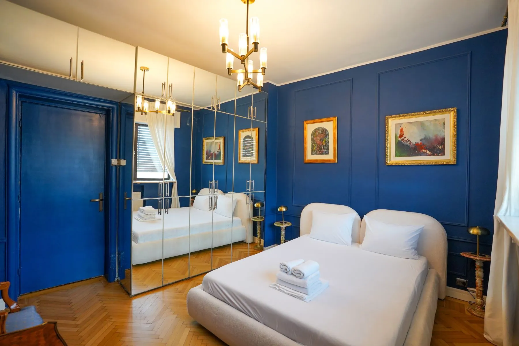 Historic blue bedroom with mirrored wardrobes and restored parquet floor