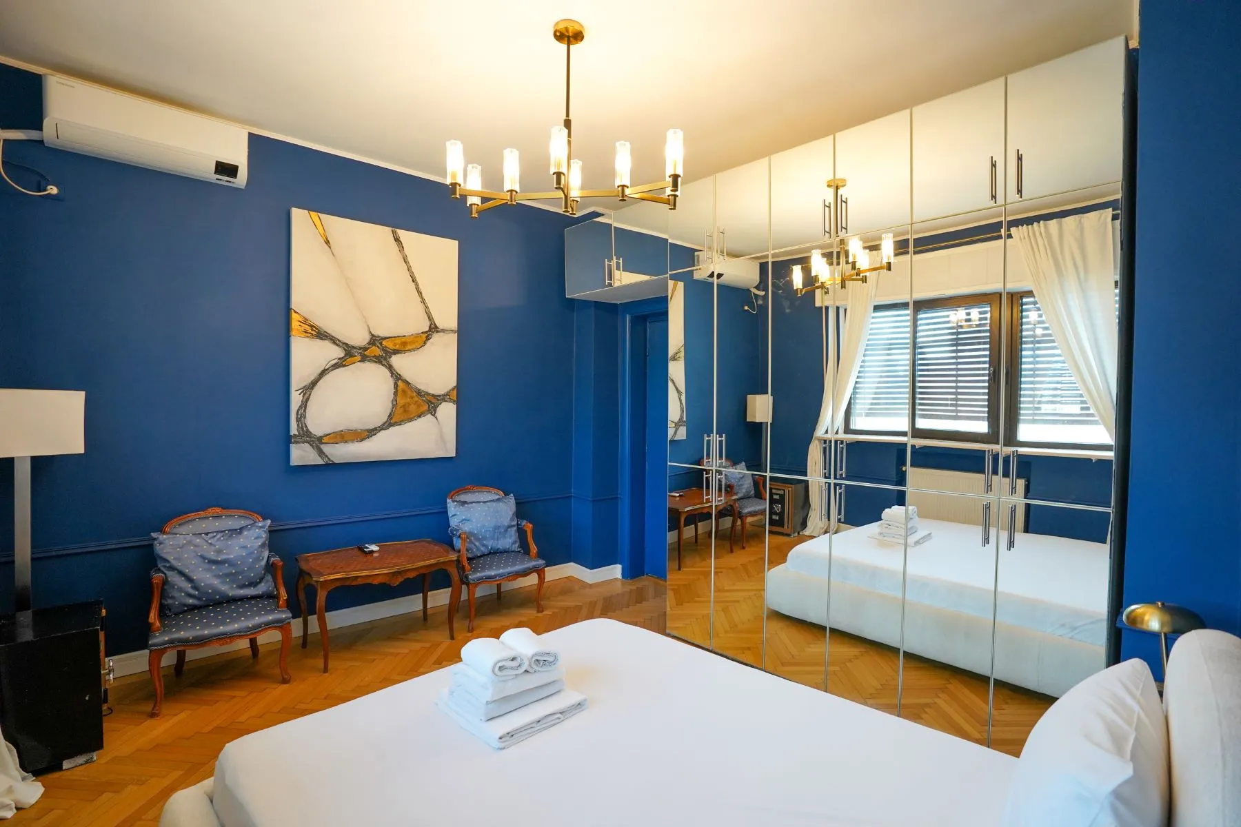 Private blue sitting area with sofa, artwork and mirrored storage
