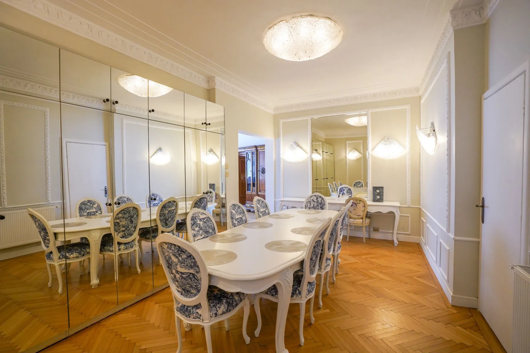 Formal mirrored dining room with a long table arranged for twelve guests