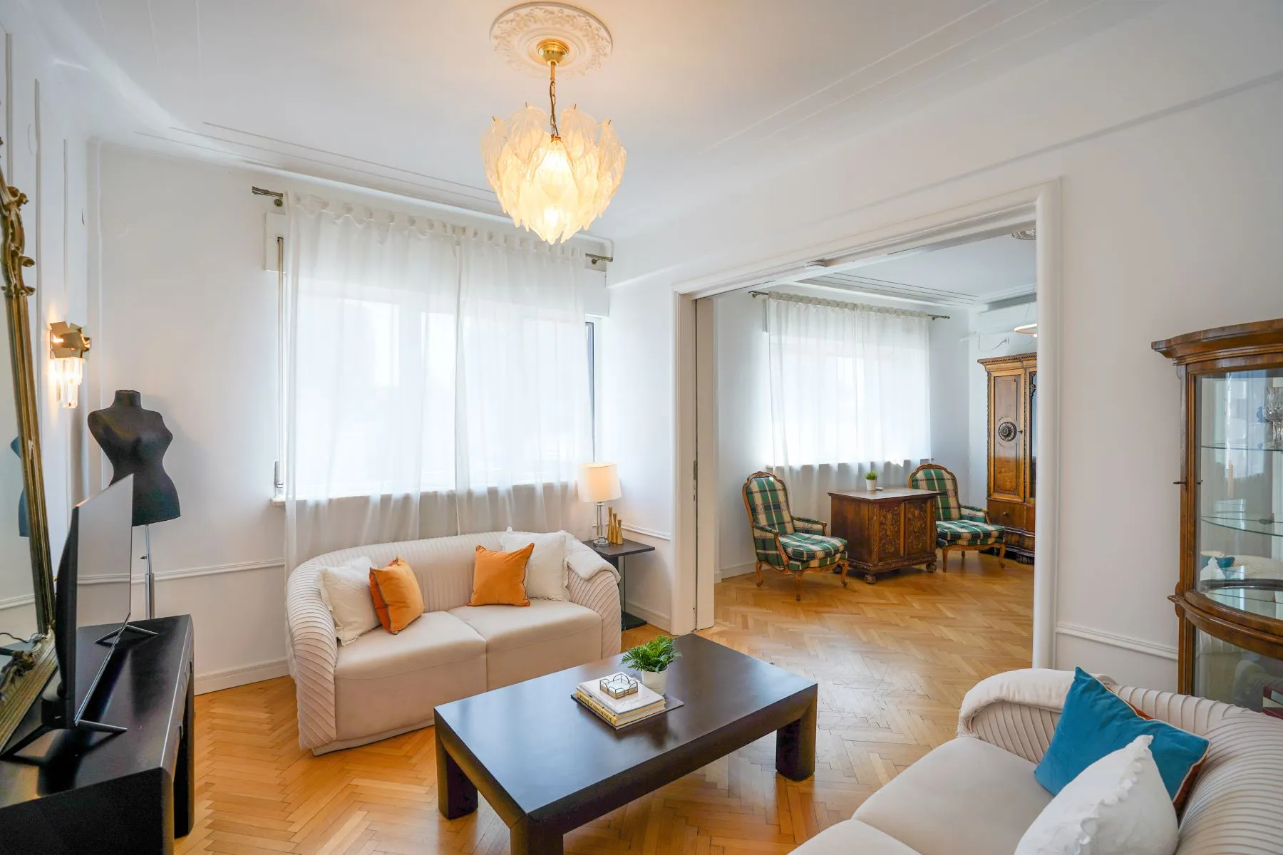 Spacious living room with multiple sofas, crystal lighting and period details