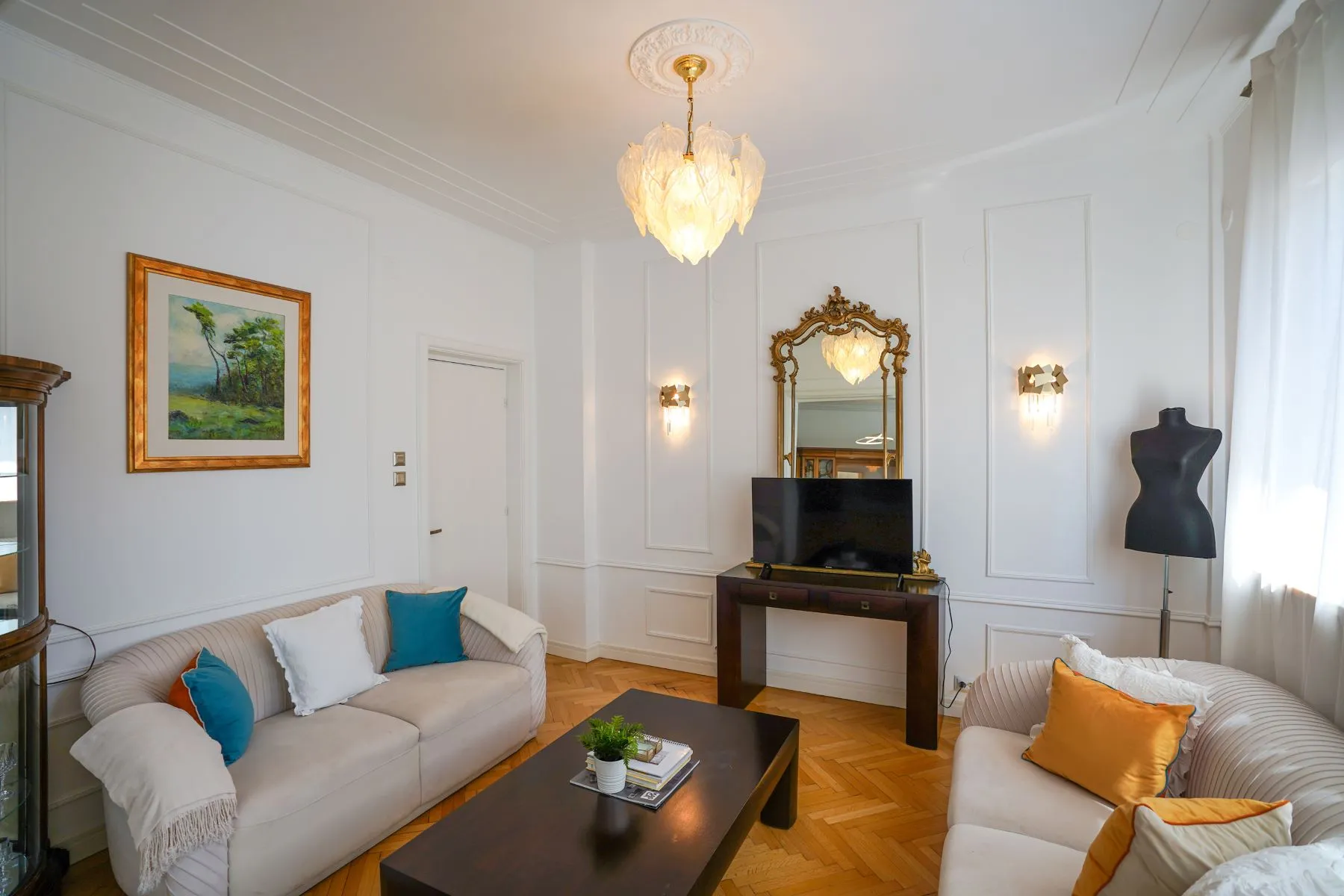 Refined reception room with classical artwork, ornate mirror and bright windows