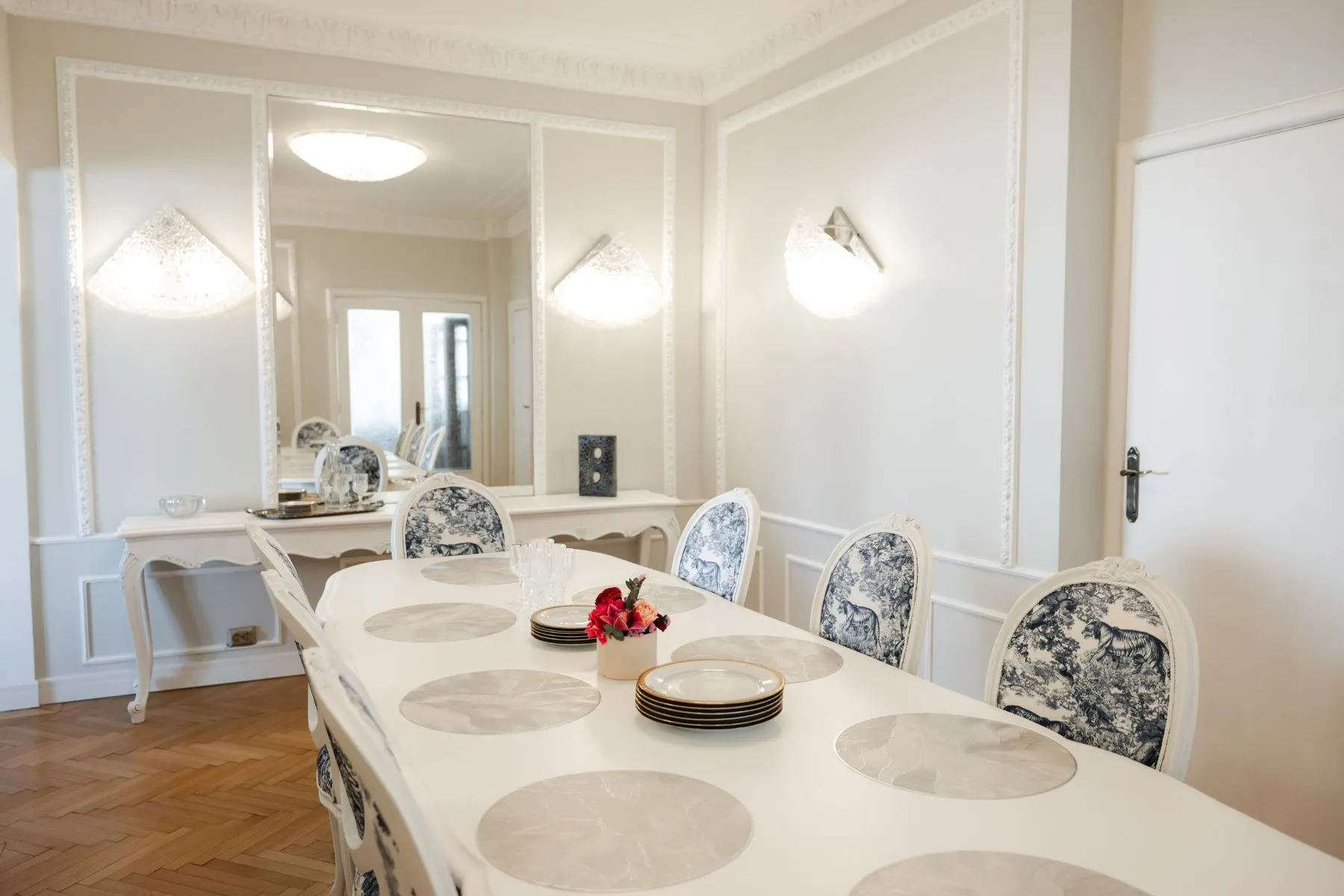 Formal dining table beneath mirrored wall panels and traditional mouldings