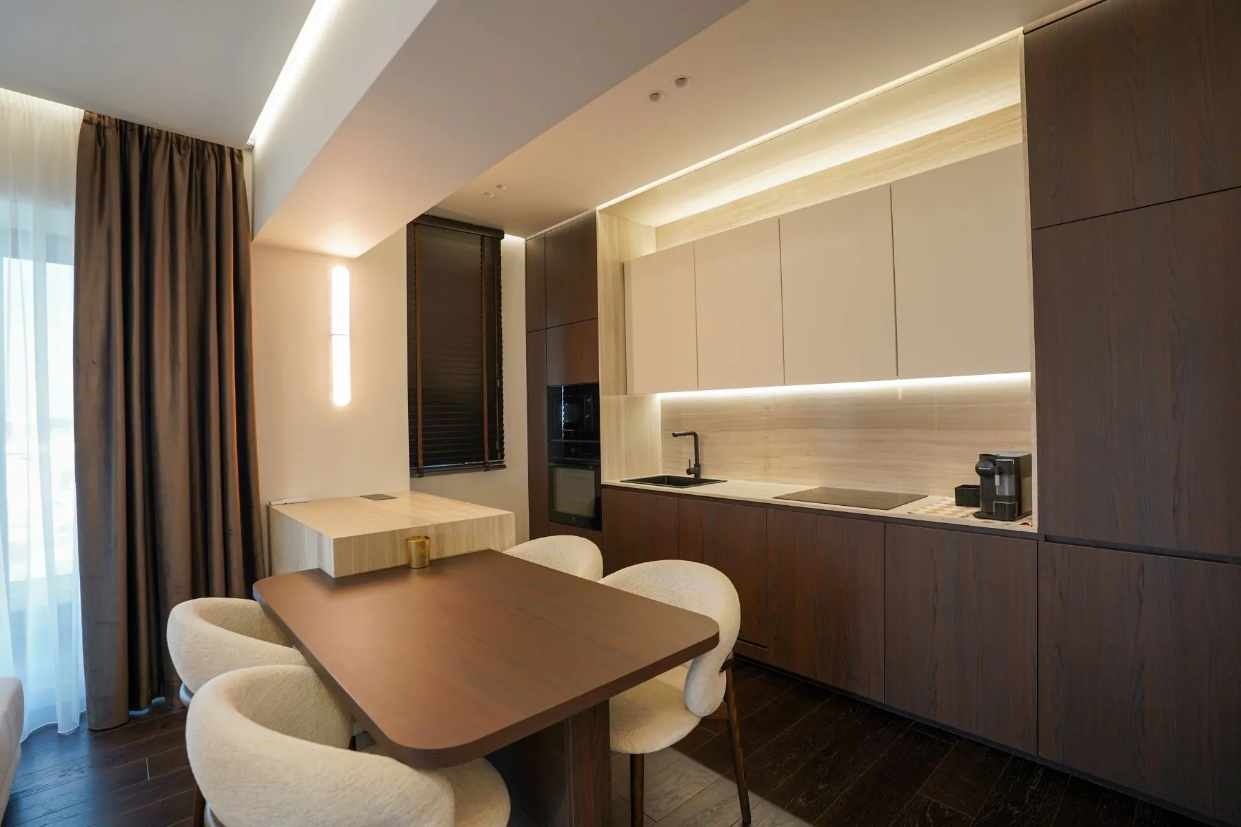 Dining area with curved upholstered chairs beside the dark timber kitchen