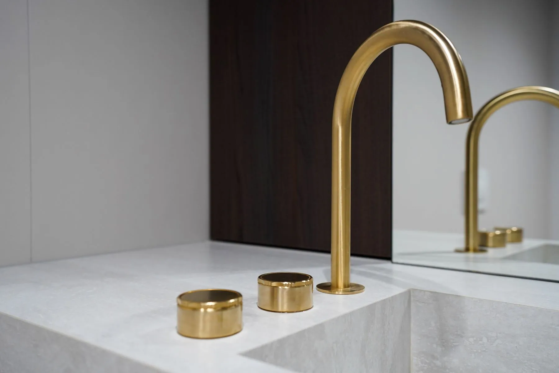 Brushed-gold basin taps set into the white stone bathroom vanity