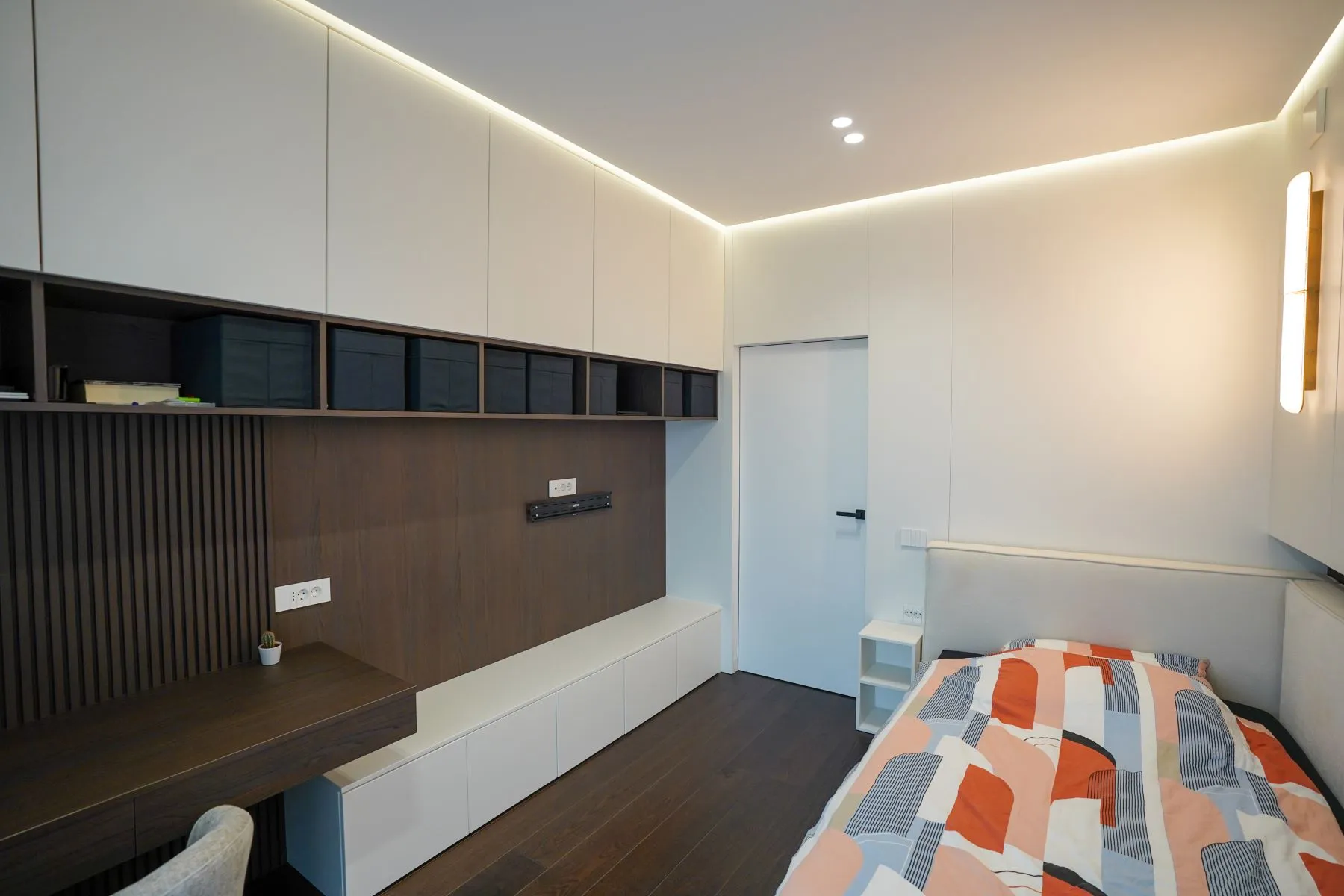 Guest bedroom with wall-to-wall desk, overhead storage and integrated lighting