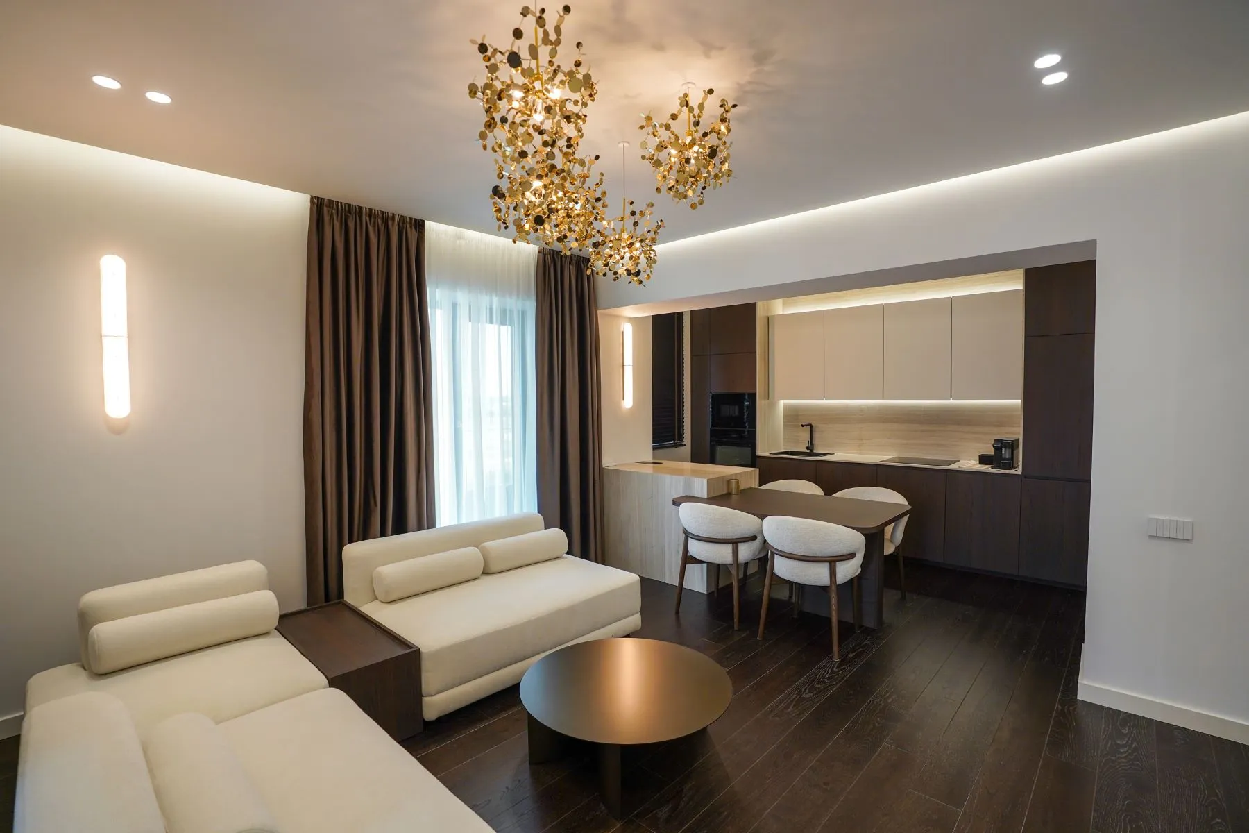 Spacious living room with cream sofas, breakfast bar and statement chandelier