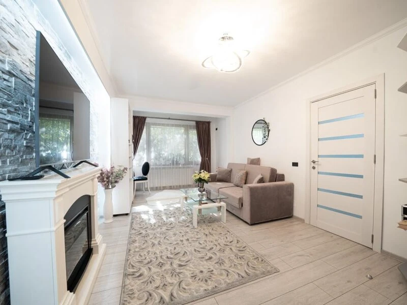 Sunlit living room with patterned rug, glass coffee table and modern interior doors
