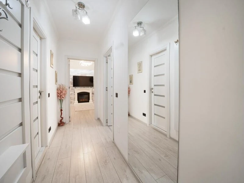 Bright apartment hallway with modern white doors and timber-effect flooring