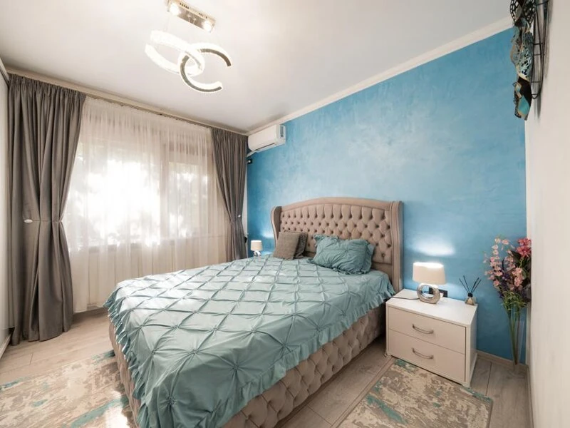 Double bedroom with blue feature wall, upholstered bed and air conditioning