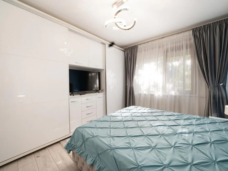 Bucharest bedroom with full-height white wardrobes and integrated television