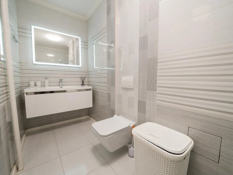 Modern bathroom with floating vanity, illuminated mirror, toilet and bidet