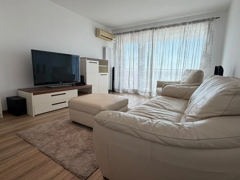 Bright Bucharest living room with white leather sofa, television and terrace doors