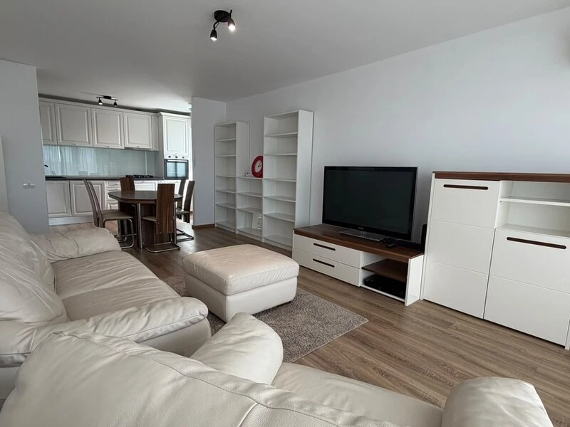 Comfortable lounge with white leather seating, television and storage cabinetry