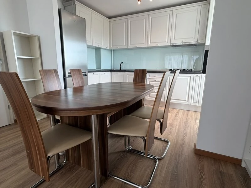 Round dining table beside the modern white kitchen and breakfast counter