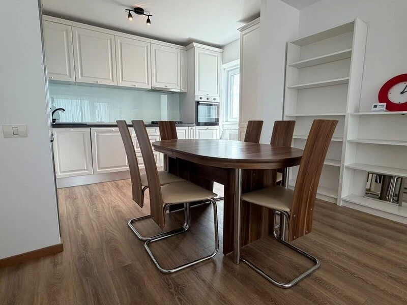 White fitted kitchen with integrated appliances and adjoining dining area