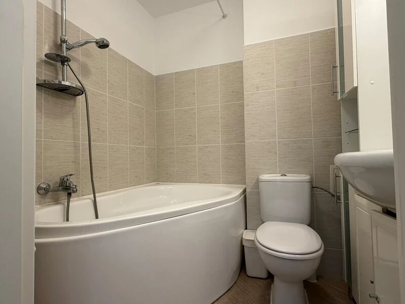 Main bathroom with curved bathtub, shower fittings and neutral tilework