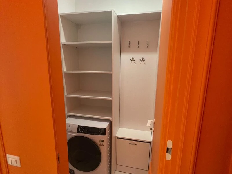 Utility storage area with washing machine, shelves and entrance coat hooks