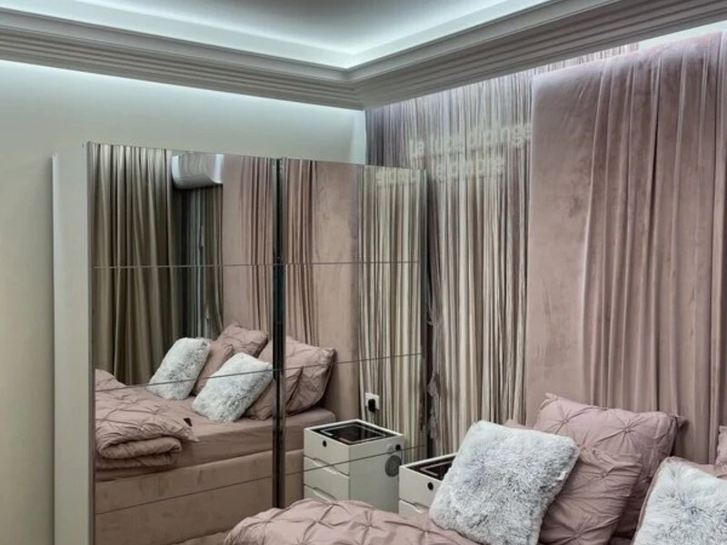 Double bedroom reflected in full-height mirrored fitted wardrobes