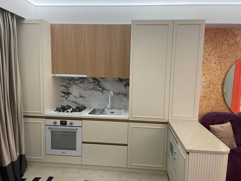 Pale fitted kitchen with gas hob, integrated oven and stone-effect worktop