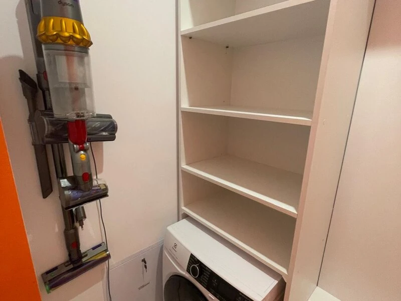 Concealed utility cupboard with shelving, washing machine and cordless vacuum