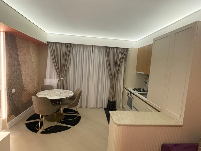 Round dining table beside the fitted kitchen and curtained balcony doors