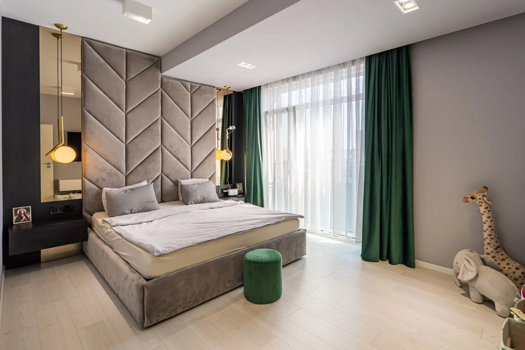 Principal bedroom with geometric upholstered wall and deep green curtains