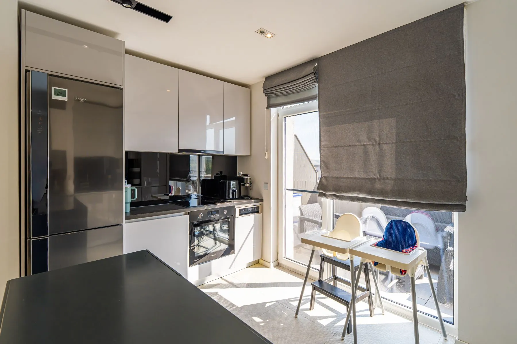 White penthouse kitchen with integrated refrigerator and sunlit dining nook
