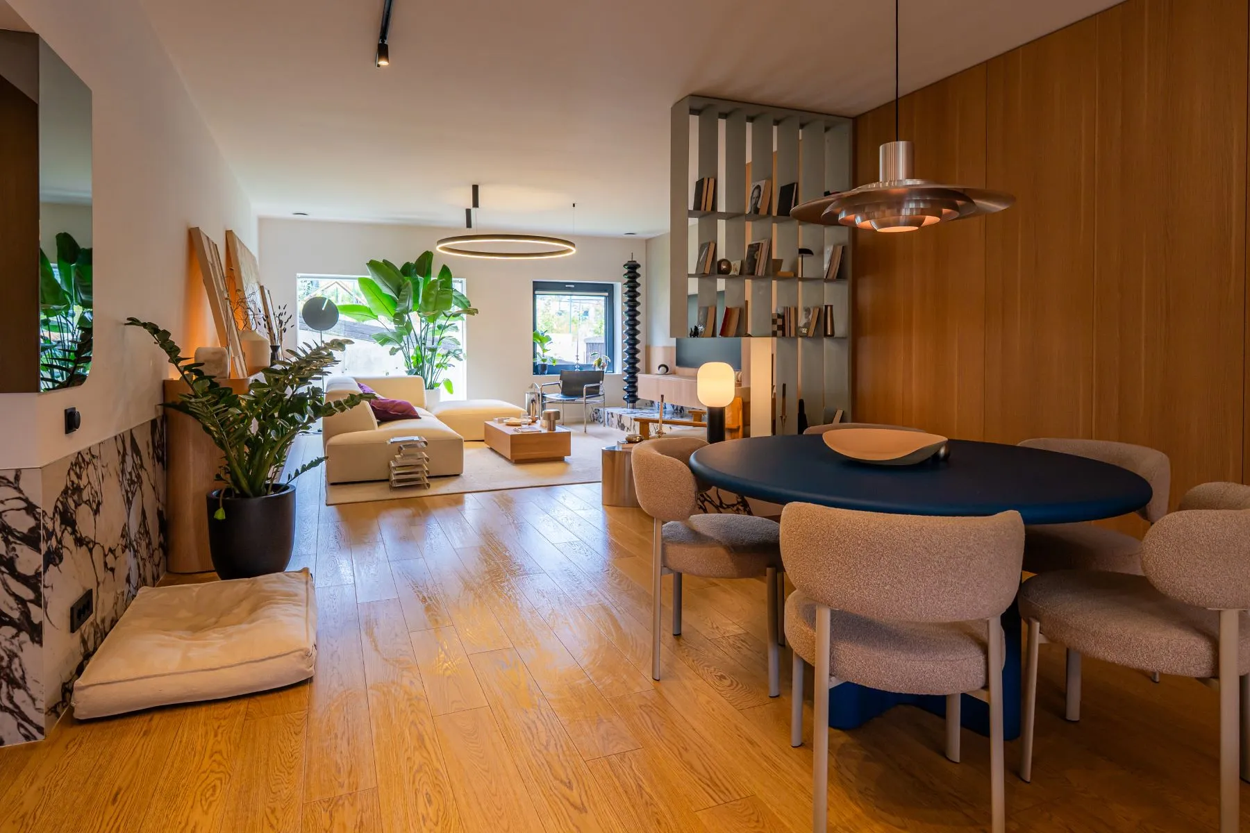 Elegant dining area with upholstered chairs and garden-facing lounge beyond