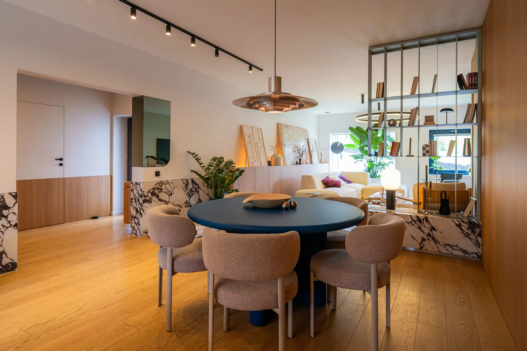 Round dining table framed by marble accents and contemporary pendant lights