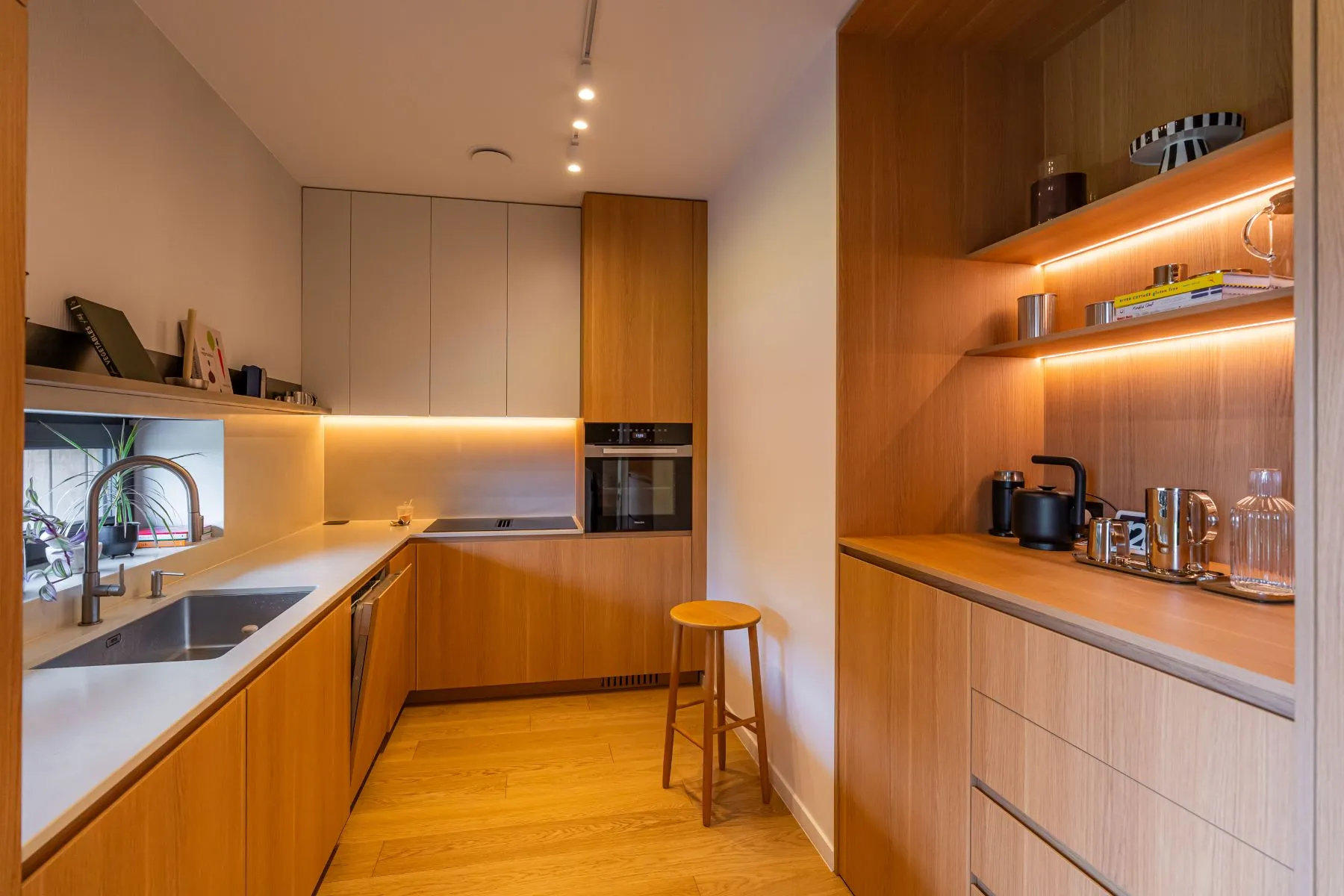 Contemporary timber kitchen with integrated appliances and illuminated worktops