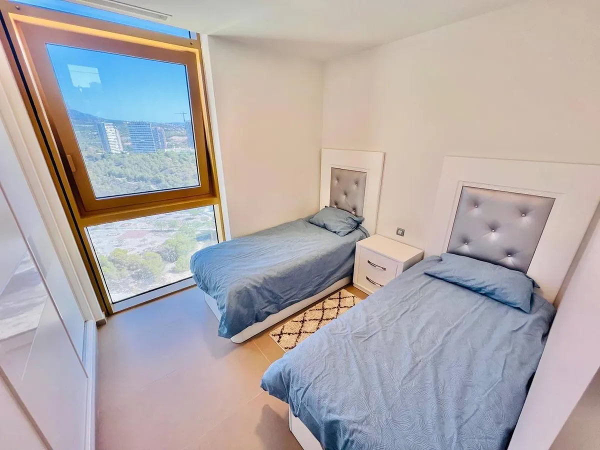 Bright twin bedroom with elevated Benidorm and mountain outlook