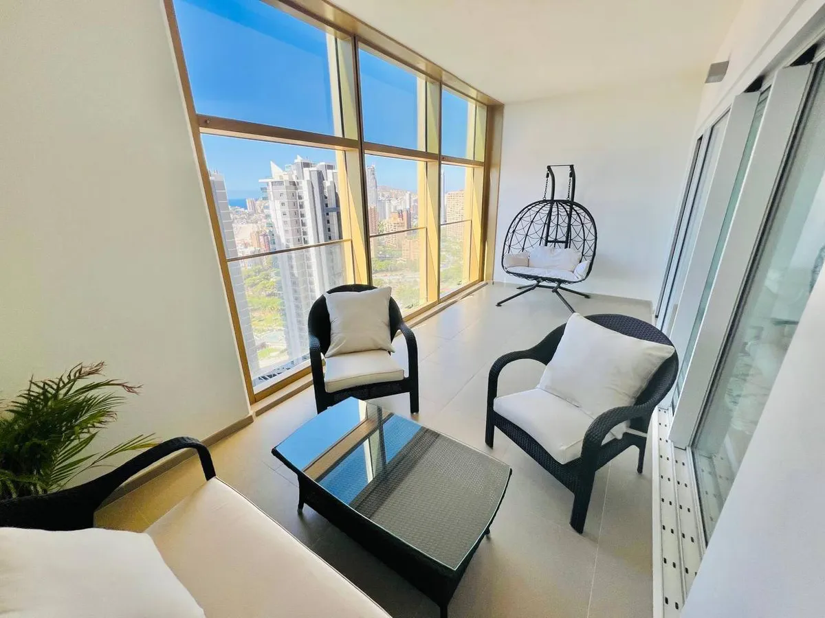 Sea-view balcony seating area with hanging chair and wide corner windows