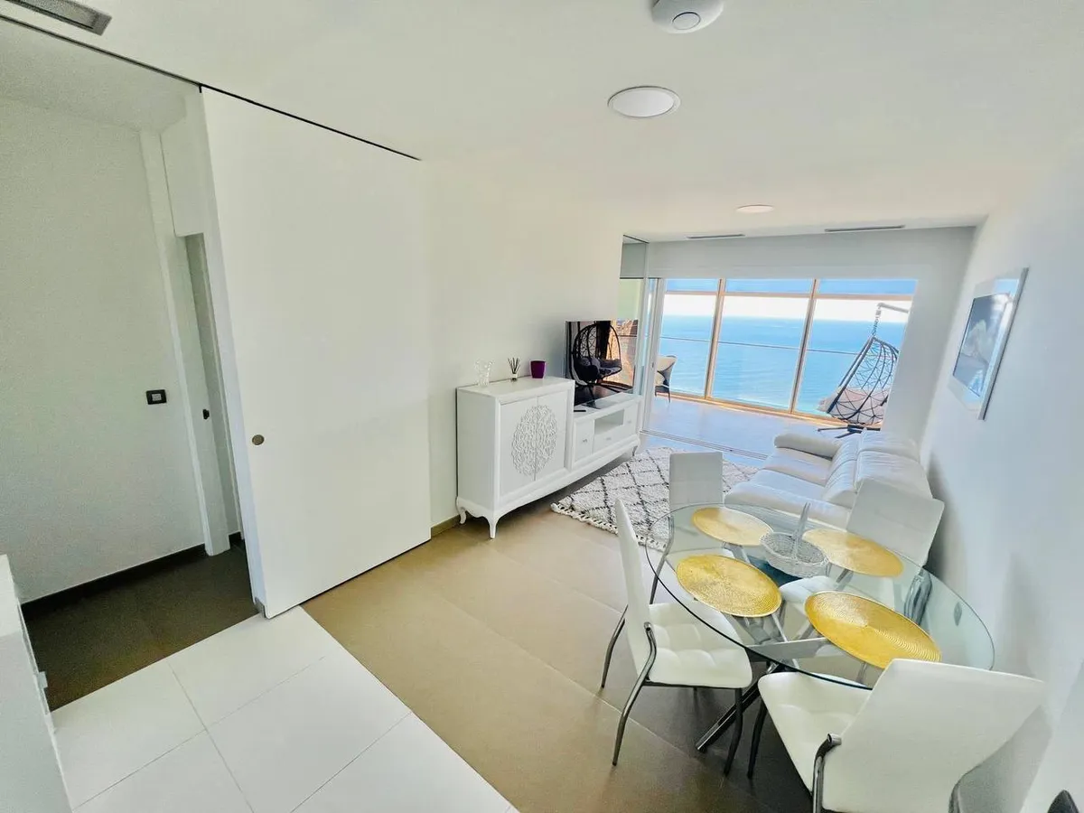 Glass dining table beside panoramic windows overlooking the Mediterranean