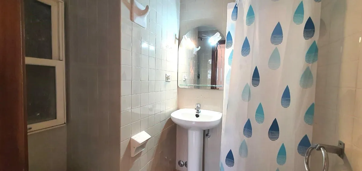 Bathroom with basin and bathtub behind a patterned shower curtain