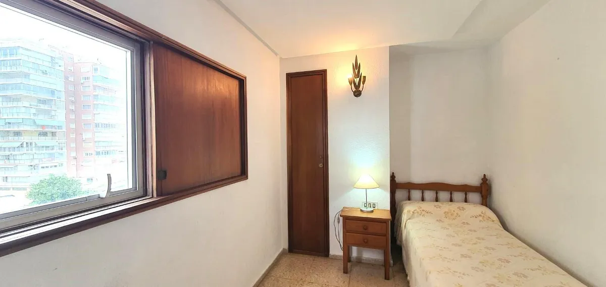 Single bedroom with bedside table and wide exterior window