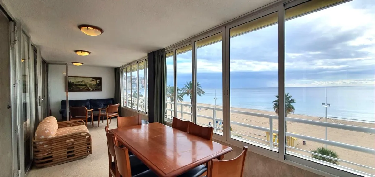 Timber dining table beside broad windows overlooking the sea