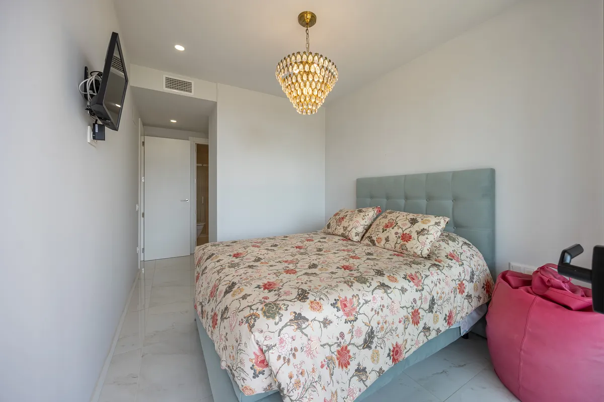 Modern double bedroom with upholstered headboard and wall-mounted television