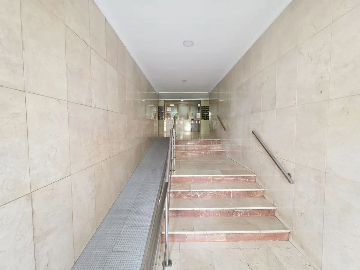 Accessible communal entrance with ramp and marble wall finishes