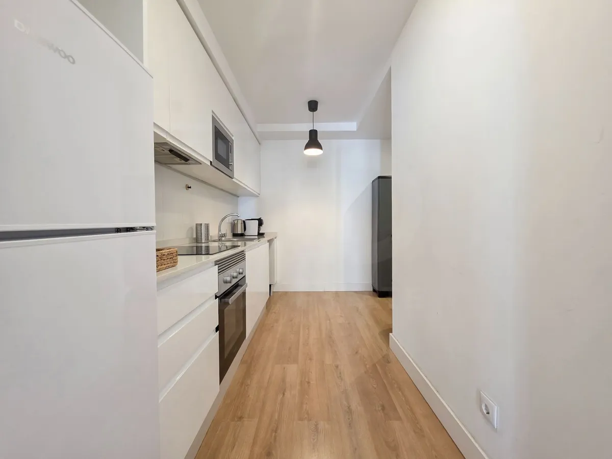 Separate white galley kitchen with integrated appliances