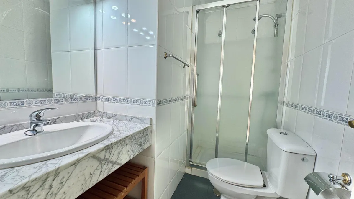 First bathroom with glass-enclosed shower and marble vanity