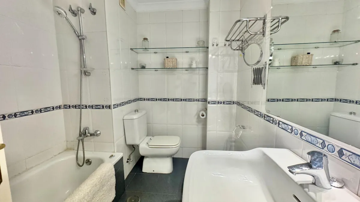 Second bathroom with bathtub, overhead shower and built-in shelving