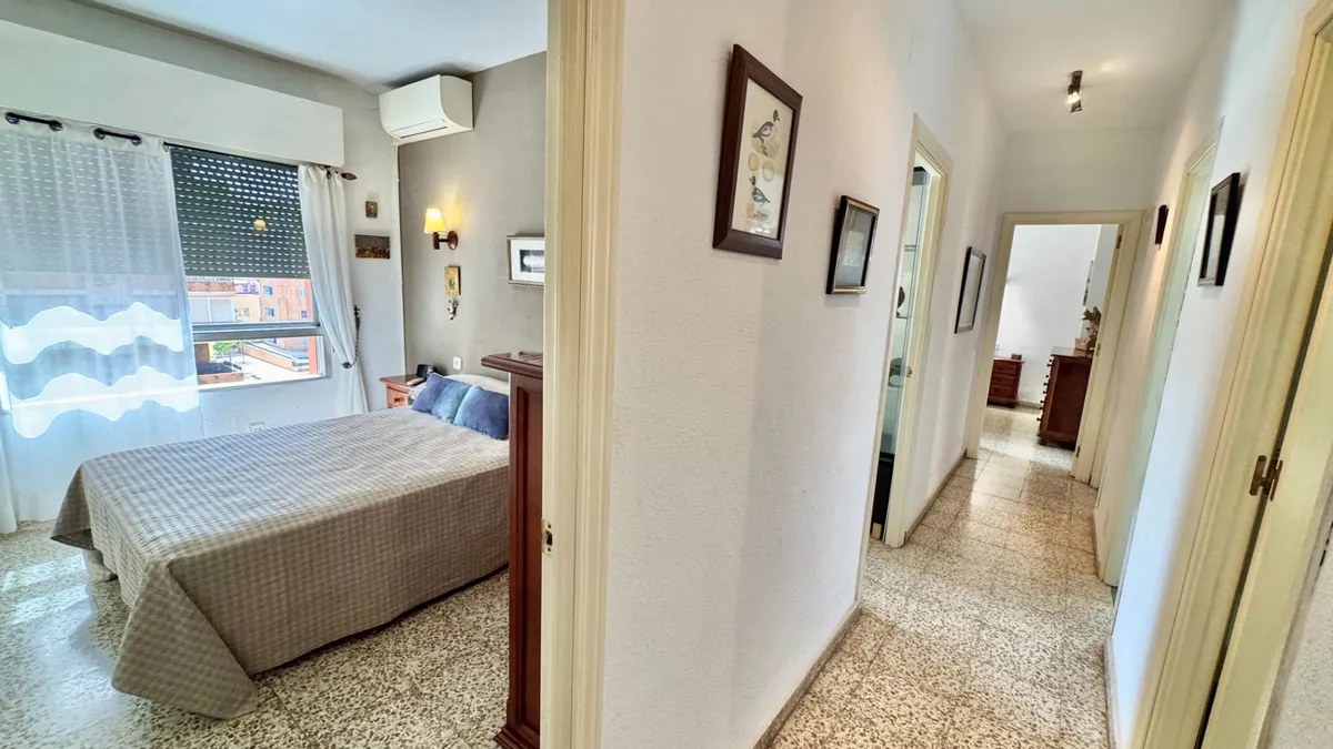 Double bedroom viewed from the hallway beside wide balcony windows