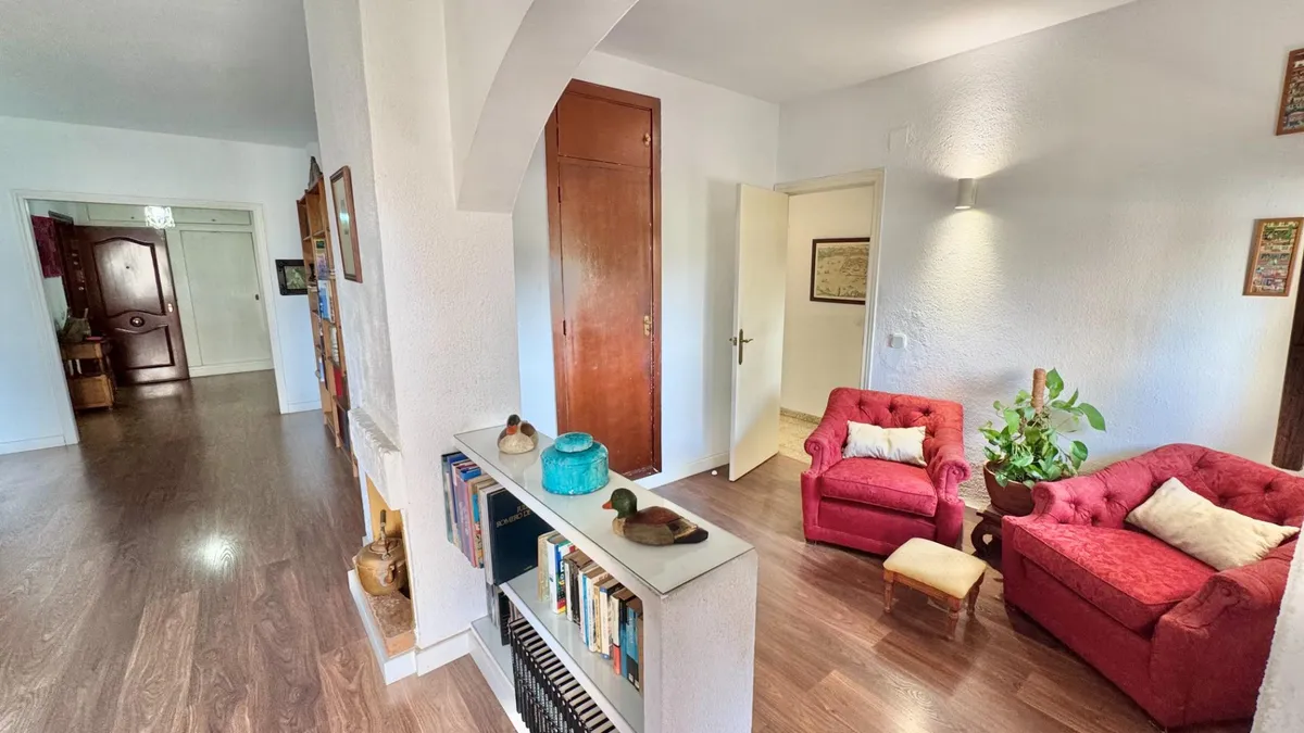 Main living room with red seating, decorative fireplace and timber floor